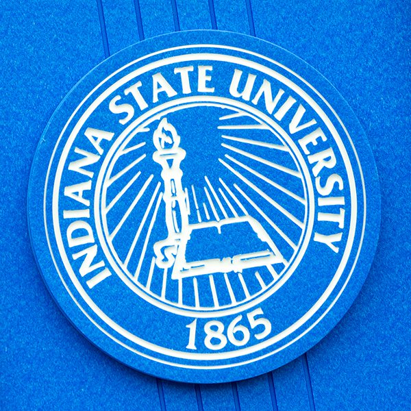 The Indiana State University seal. It is white on a blue background and features a torch, an open book, and the year 1865.