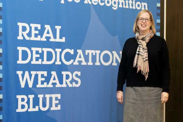 a female ISU staff member standing in front of a banner that reads Real Dedication Wears Blue