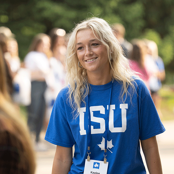 A female student with blonde hair wearing a blue ISU T-shirt smiles