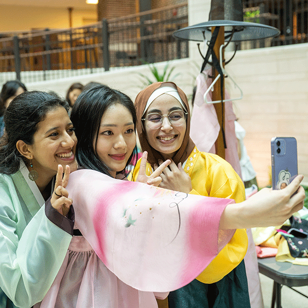 Three female students take a selfie while holding up their fingers in a peace sign