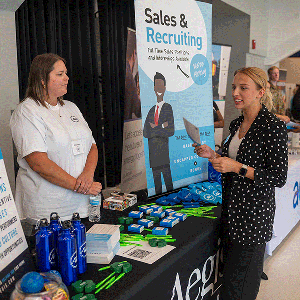 A photo of two women talking with one another at a job fair.