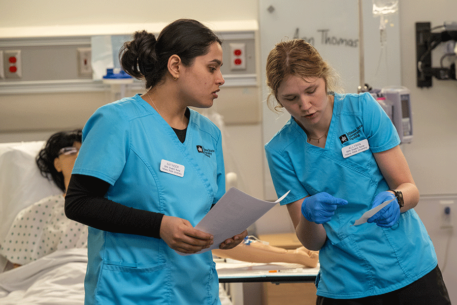 Two nursing students, wearing their ISU scrubs, gain knowledge and skills in one of the Nursing Learning Resource Center skill labs at Indiana State University.