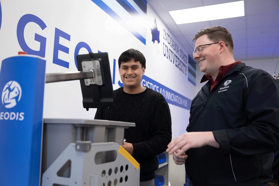 Two individuals work with a machine in the Geodis Logisitics 4.0 Innovation Hub