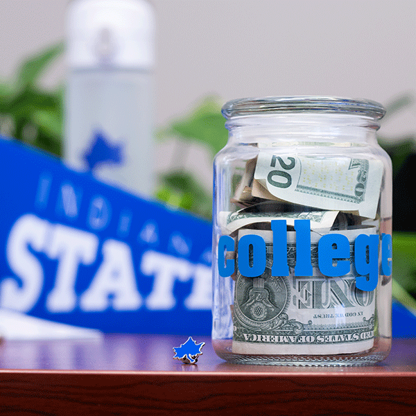 A jar filled with United States currency on a table with a blue Indiana State University penant in the background.  