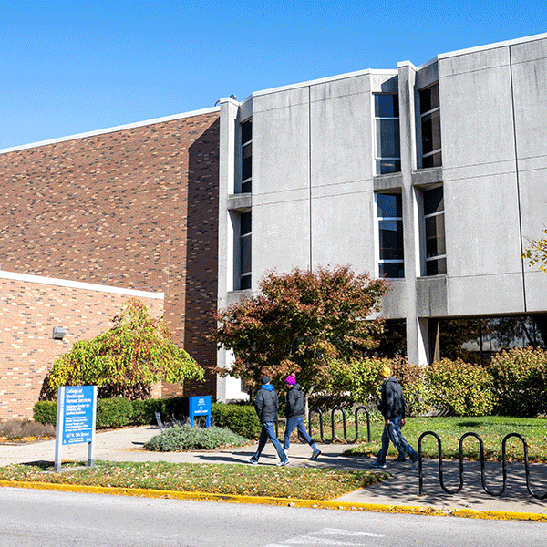 Three students walk past the front of the ISU Health Center building on a summer day.