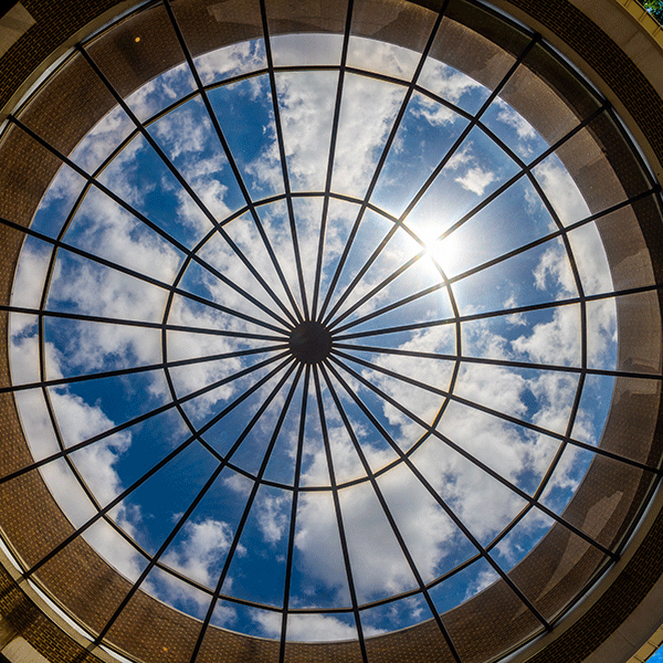 Image of the roof of the rotunda in Hulman Memorial Student Union with clouds and a sunburst in the glass ceiling.