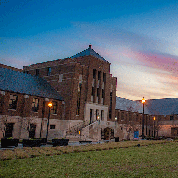 Evening image of Tirey Hall with the sculpture Chorus of Trumpets visible.