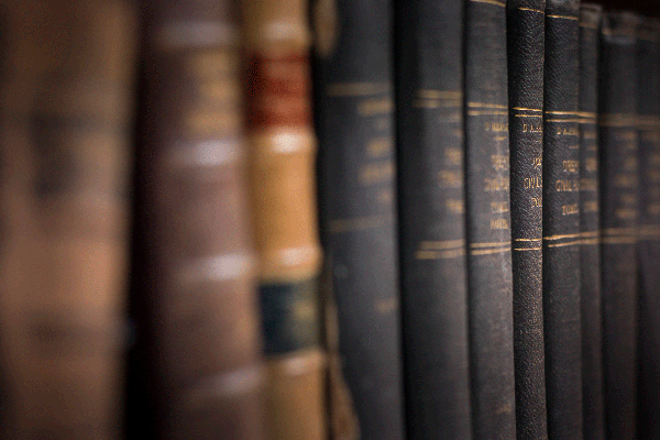 A row of aged books on a bookshelf that have the appearance of legal books.