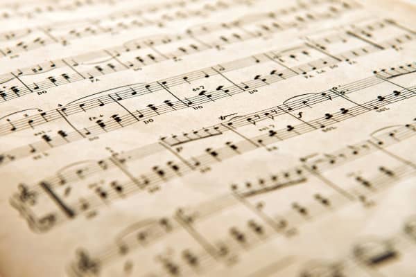 A piece of white sheet music with black musical bars and notes on it. The image has an angled, upside-down view.