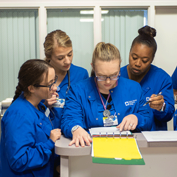 A group of six nursing students all look over a chart