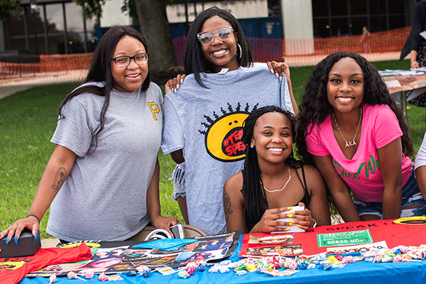 A group of African American students pose for a photo while sitting at a table during the annual Street Fair at the Charle Brown African American Cultural Center. 