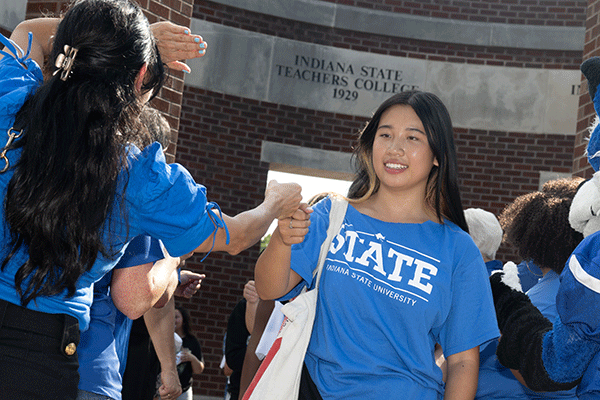 A student participates in the tradition of March Through The Arch, where freshman students walk through Oakley Plaza and greet members of the faculty and administration during Welcome Week.