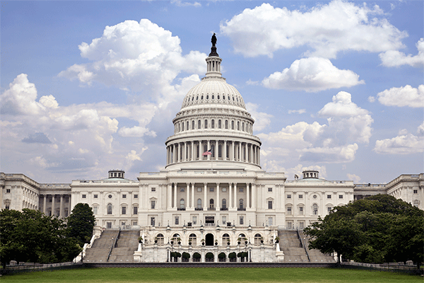 Photo of the US Capitol building with blue sky and clouds.  