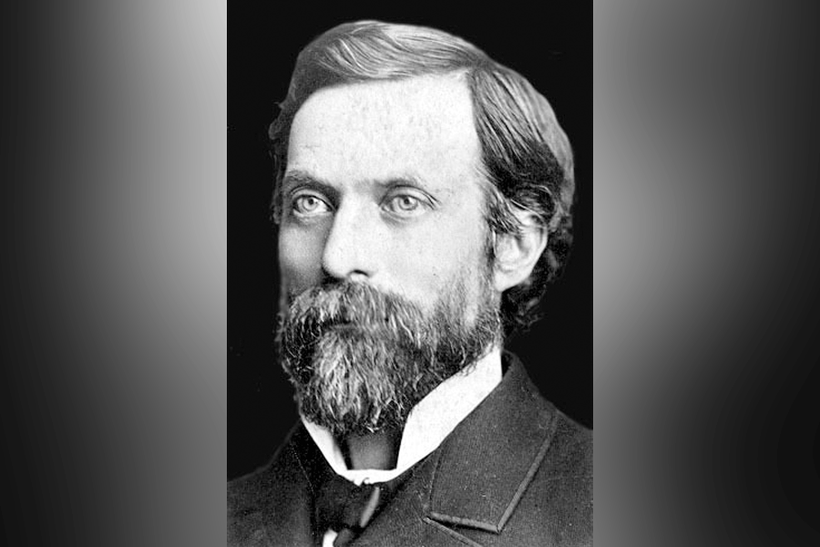 A black-and-white photograph of a man (President George Pliny Brown) with short hair and a full beard and mustache. He looks ahead and to the left. He wears a suit with a white collar. A grey border is around the photograph.