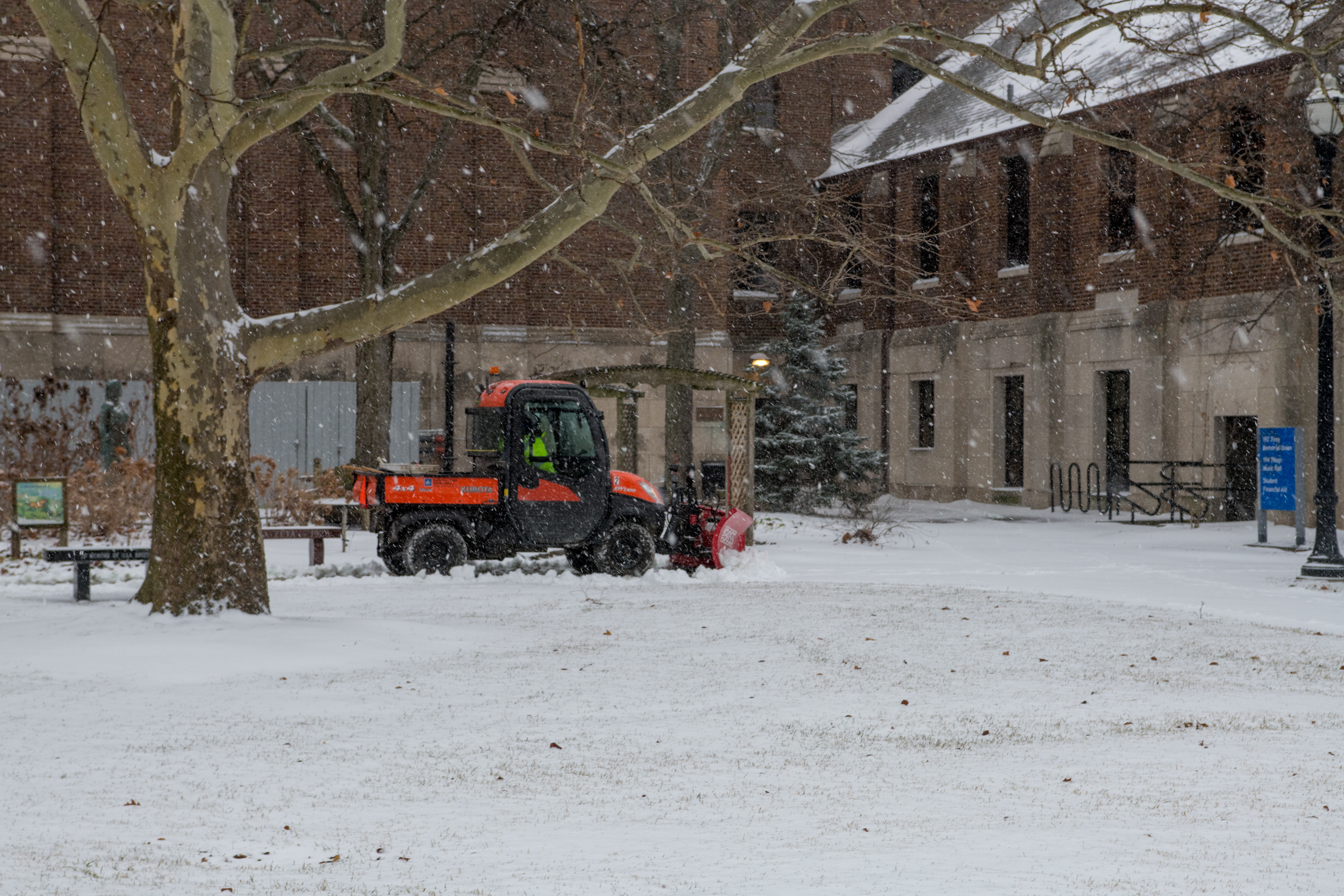 Image of a utility vehicle plowing snow on campus