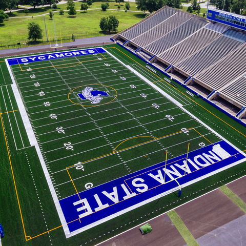 Aerial view of the Indiana State University football field with 'Sycamores' and 'Indiana State' painted on the turf. The stadium seating is visible in the background.