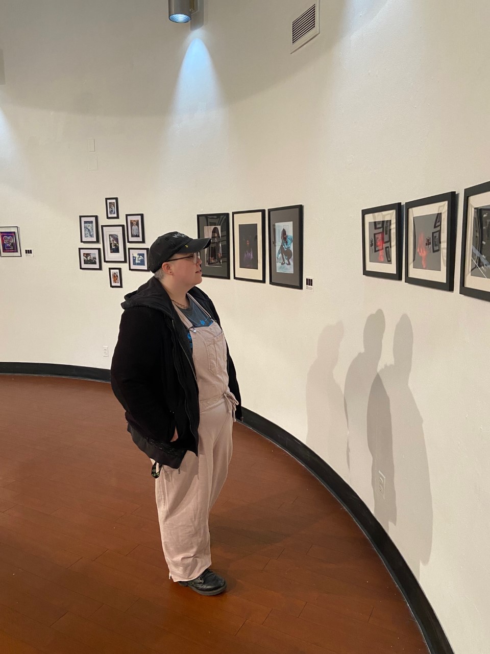 a male visitor in coveralls looking at photographs in a gallery