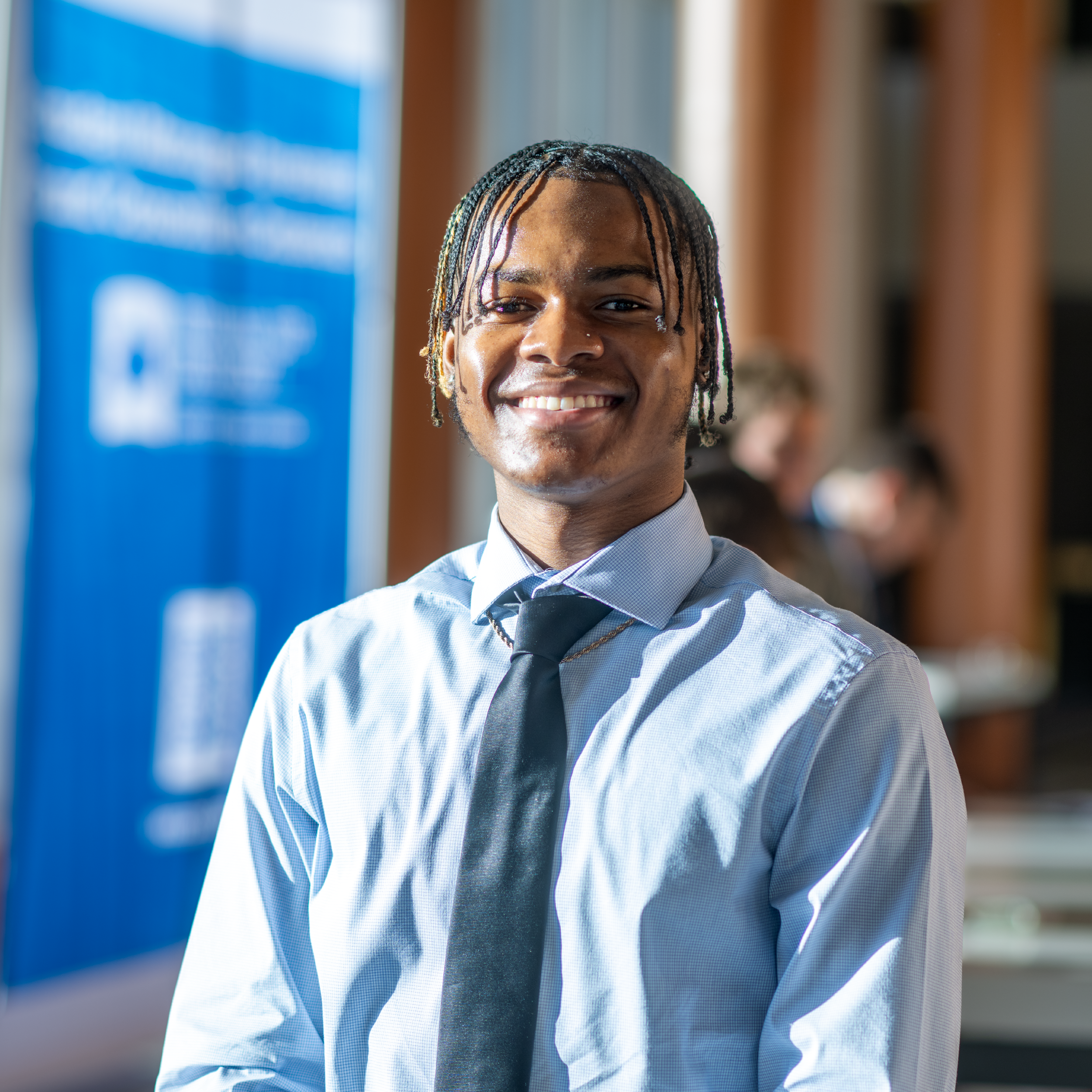 Student standing in front of a blue banner