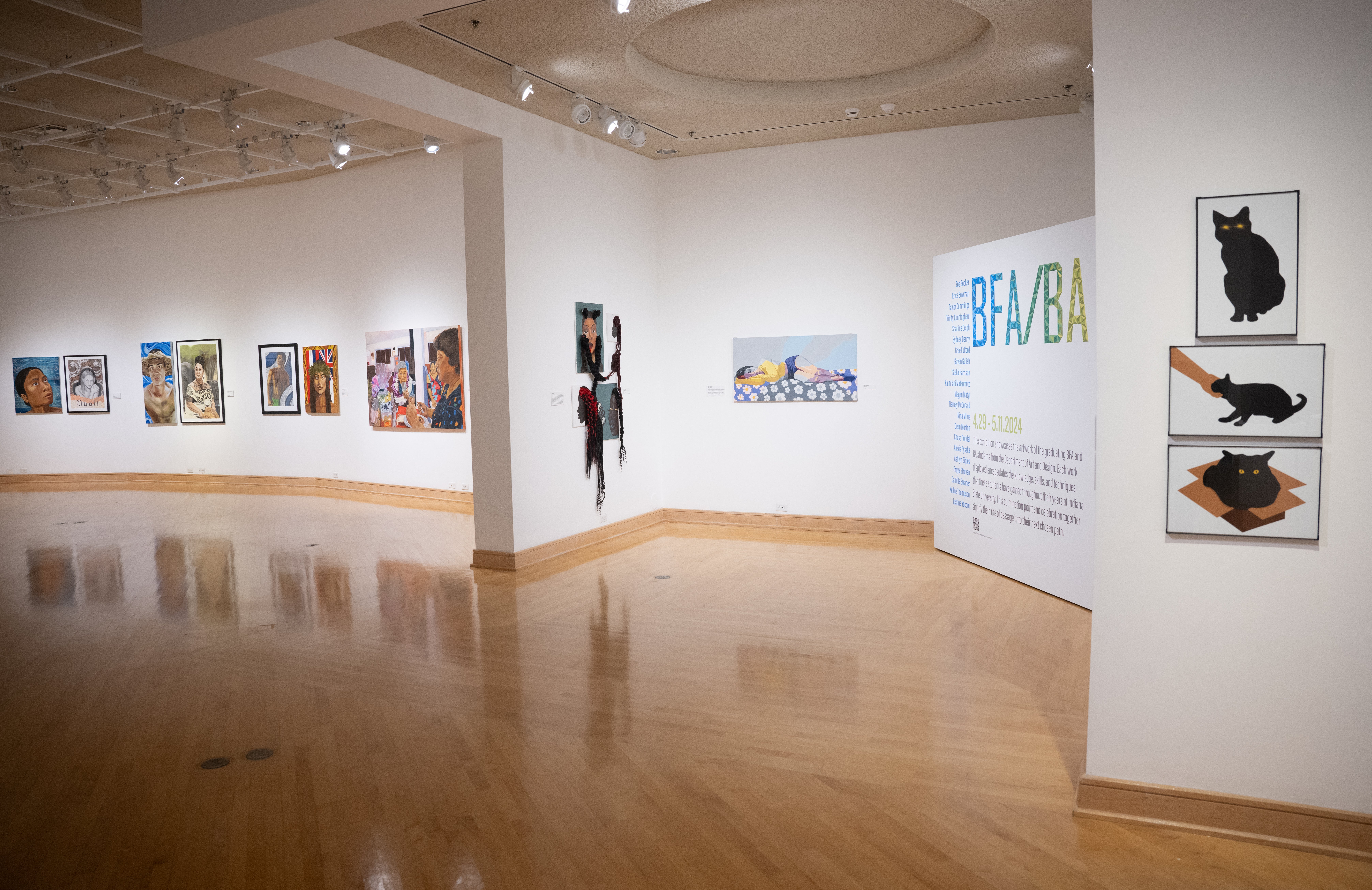 Gallery space with diverse paintings including portraits and an abstract figure, with a large BFA/BA exhibition sign on a white wall.