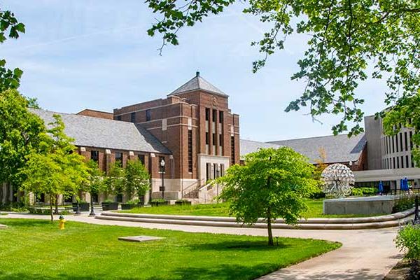 An image of Tirey Hall from across the quad during summer. Parsons Hall and the Trumpets artwork are also visible in the distance.