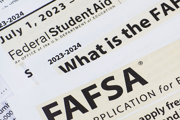 Close-up of printed documents related to the FAFSA (Free Application for Federal Student Aid) for the 2023-2024 academic year. The text highlights key phrases such as 'What is the FAFSA,' 'Federal Student Aid,' and application dates from July 1, 2023, to June 30, 2024.