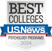 Logo of U.S. News & World Report featuring the text 'BEST COLLEGES', 'USN&WR', and 'Psychology Programs 2024' on a badge with a gray and white color scheme and blue and red ribbons.