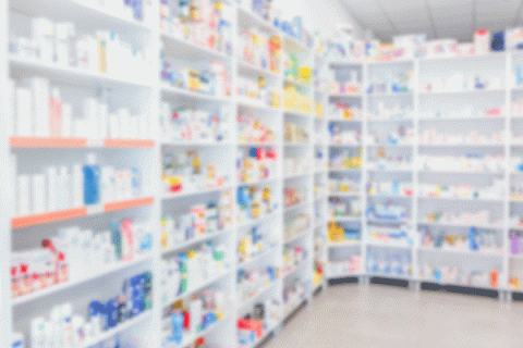 A blurry image of pharmacy shelves filled with various medicines.