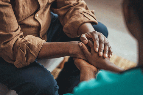 Two pairs of human hands are intertwined in a show of emotional support.