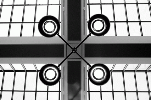 Black and white image showing a center lamp post with four circular lights around the center.  