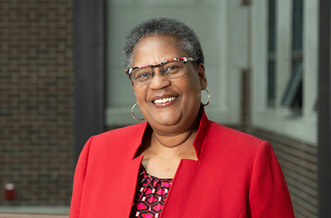 “Portrait of a woman wearing glasses and a red jacket, smiling indoors.”